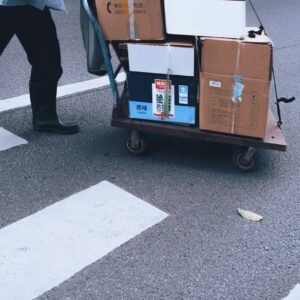 Person pulls a cart with boxes across a crosswalk.